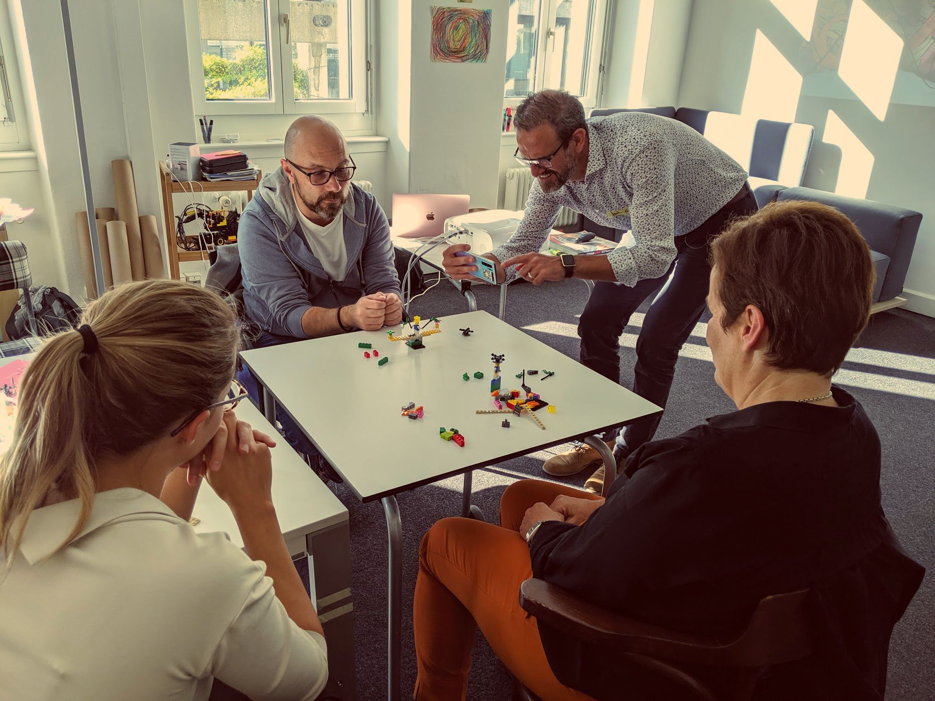 Teilnehmende bauen im Daily Play Training LEGO® Serious Play® Modelle an einem Tisch