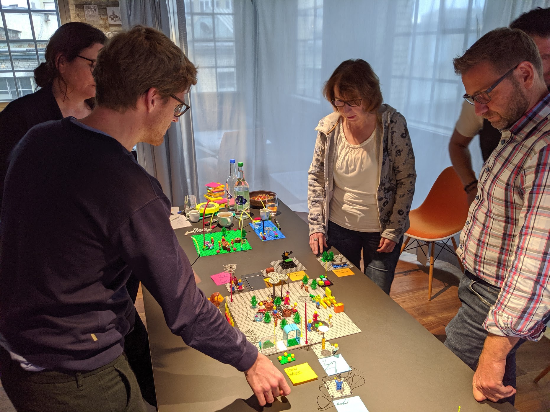 Menschen bauen gemeinsam mit LEGO Steinen an einem Tisch